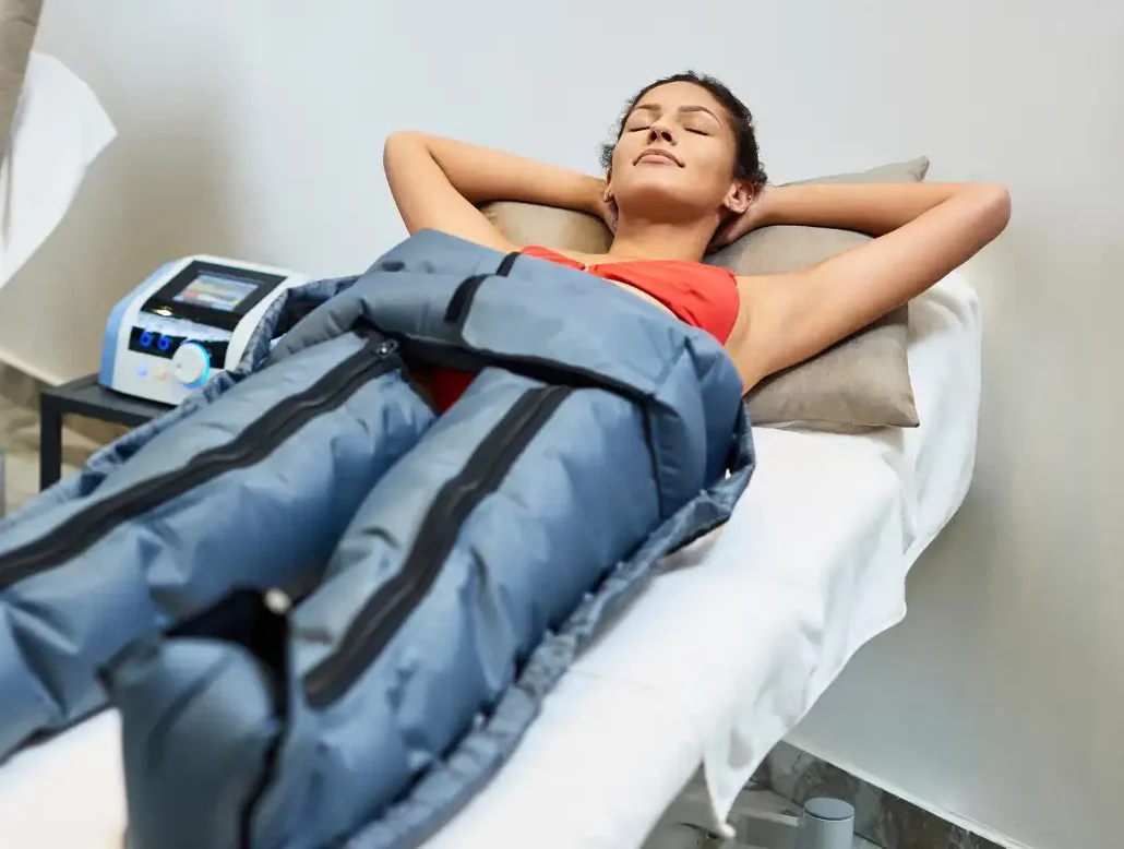 Mujer relajada con los ojos cerrados disfrutando de una sesión de presoterapia cómoda y placentera