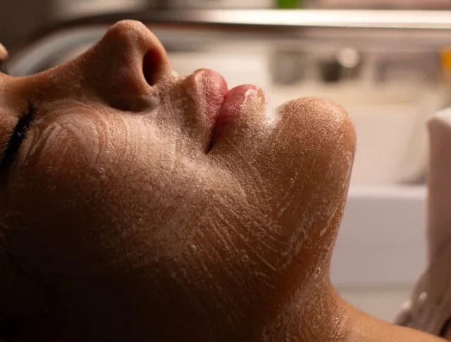 Aplicación de crema protectora para sellar la hidratación y reforzar la barrera de la piel en un tratamiento facial.